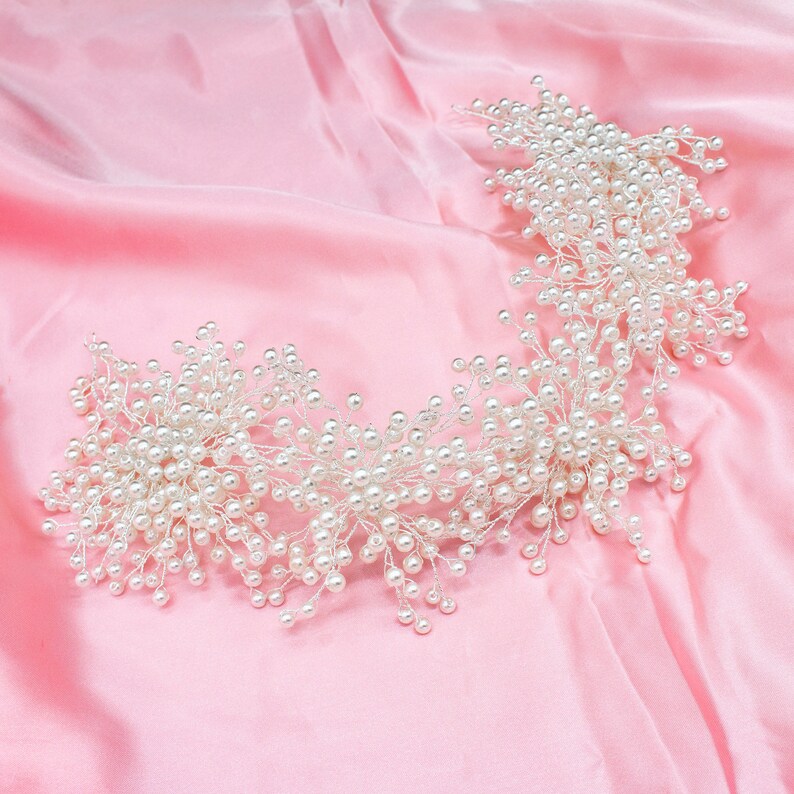May include: A delicate pearl hairpiece with a floral design. The hairpiece is made of small white pearls and silver wire, and it is arranged in a cascading pattern. The hairpiece is perfect for a wedding or other special occasion.