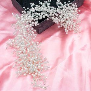 May include: A long, white pearl garland with a delicate, floral design. The garland is made of small, white pearls strung on thin wire. It is perfect for adding a touch of elegance to any occasion.
