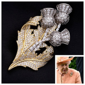 May include: A gold and silver brooch featuring a cluster of three thistle flowers, each adorned with sparkling clear rhinestones. The thistle flowers are set on a leafy stem, also encrusted with rhinestones.