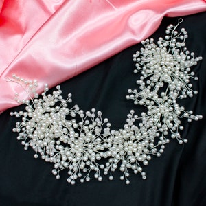 May include: A delicate pearl hairpiece with a floral design. The hairpiece is made of silver wire and white pearls. It is perfect for a wedding or special occasion.