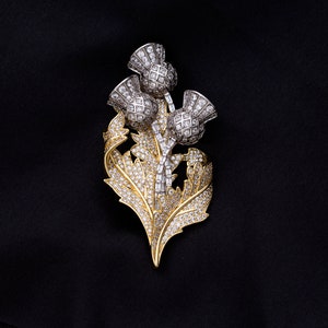May include: A gold and silver brooch with a thistle design. The thistle is made of clear rhinestones and has a detailed design. The brooch is a great way to add a touch of elegance to any outfit.