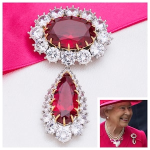Peut inclure: Une broche en rubis rouge et diamants avec un pendentif en forme de larme. La broche est sertie d'argent et d'or et présente un grand rubis de forme ovale entouré de diamants plus petits. Le pendentif est un rubis en forme de larme entouré de diamants plus petits.