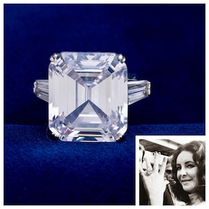 May include: A large, clear emerald-cut diamond ring with baguette side stones, set on a silver band. The ring is displayed on a deep blue velvet surface. A black and white photo of a woman wearing the ring is in the corner.