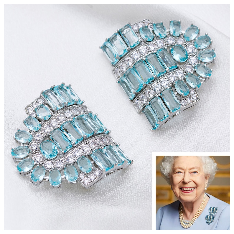 K&ouml;nnte beinhalten: Ein Paar Ohrringe aus Silber und blauem Aquamarin. Die Ohrringe bestehen aus einer Reihe von rechteckigen und ovalen Steinen, die in Silber gefasst sind.