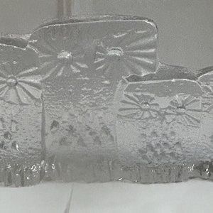 May include: A set of four clear glass owls, each with a unique design, arranged in a row. The owls are made of textured glass and have a frosted appearance.