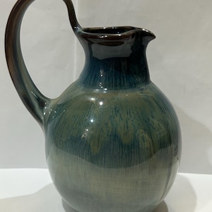 May include: A blue and brown ceramic pitcher with a rounded body and a curved handle.