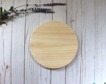 May include: A round, unfinished wooden disc with a smooth surface. The disc is light brown in colour and has a natural wood grain.