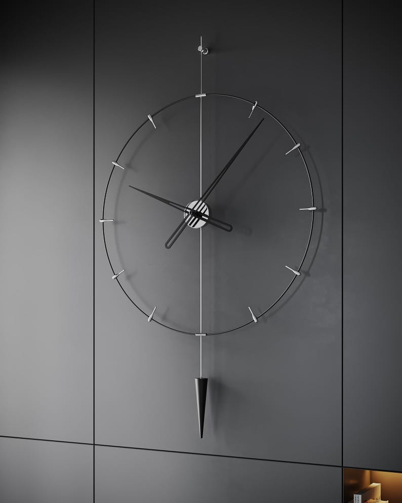 May include: A contemporary wall clock with a minimalist aesthetic. The clock has a transparent face with black hands and hour markers. A black, cone-shaped pendulum hangs beneath. The clock is mounted on a grey wall.