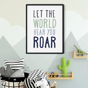 Pode incluir: Uma impressão emoldurada em preto com o texto "Let the world hear you roar" em um esquema de cores azul claro, verde e azul escuro. A impressão está pendurada em uma parede com um padrão geométrico azul claro e cinza.