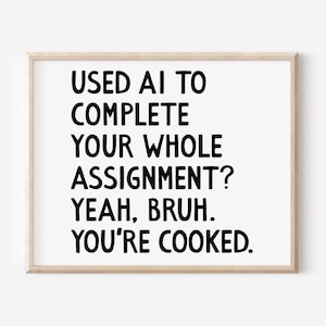 May include: A framed print with the text "USED AI TO COMPLETE YOUR WHOLE ASSIGNMENT? YEAH, BRUH. YOU'RE COOKED." in bold black letters on a white background. The frame is a light wood color.