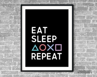 May include: Black and white framed print with the text "Eat Sleep  △○×□ Repeat" in white on a black background. The symbols are in different colors: blue, pink, and light blue.