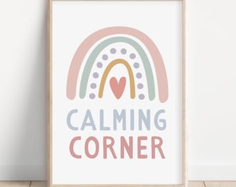 Puede incluir: Un cuadro enmarcado con un diseño de arcoíris pastel, un corazón y las palabras "CALMING CORNER". La obra de arte está en un marco de madera, ideal para una guardería o habitación infantil. Los colores son suaves.