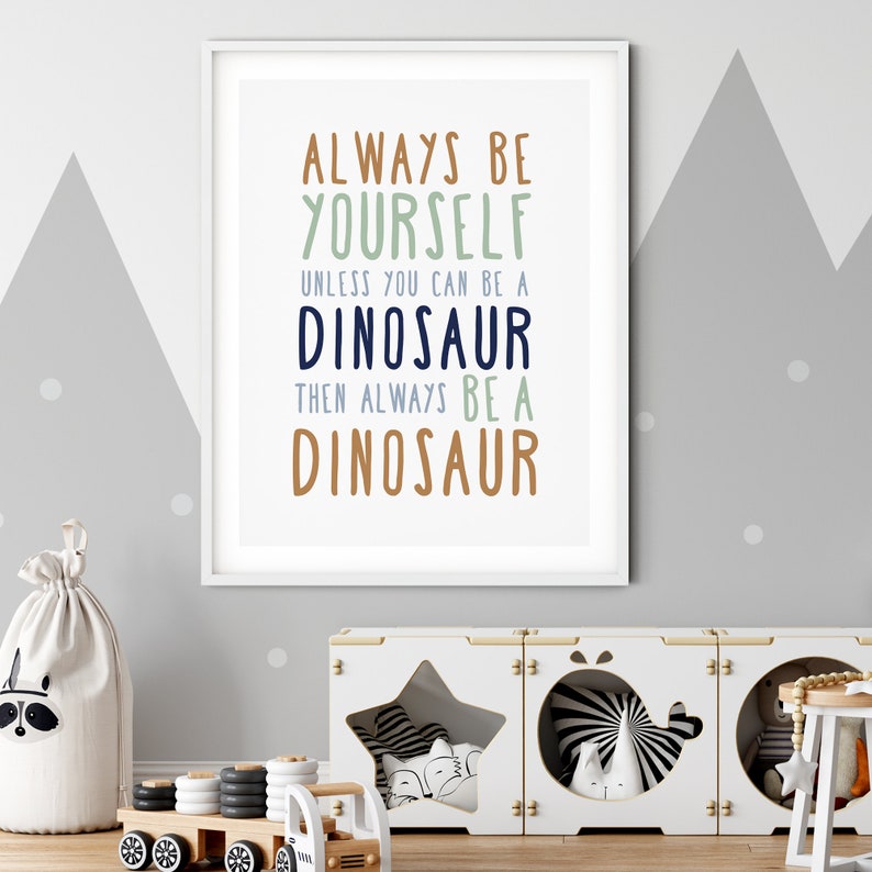 May include: A framed print with the text "Always be yourself unless you can be a dinosaur then always be a dinosaur" in blue, green, and brown text on a white background.