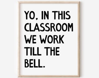 May include: A framed print with the text "YO, IN THIS CLASSROOM WE WORK TILL THE BELL." The text is in bold, black letters on a white background. The frame is a light wood color.