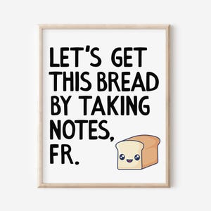Peut inclure: Impression encadrée avec le texte "LET'S GET THIS BREAD BY TAKING NOTES, FR." en noir. Un pain de mie de dessin animé avec un visage souriant est dans le coin inférieur droit. Le cadre est de couleur bois clair.