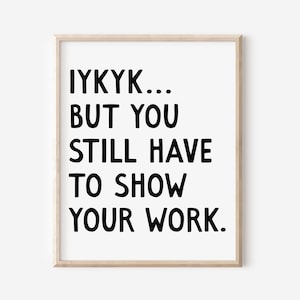 Puede incluir: Una impresión enmarcada con el texto "IYKYK... BUT YOU STILL HAVE TO SHOW YOUR WORK" en letras negras en negrita sobre un fondo blanco. El marco es de color madera clara.