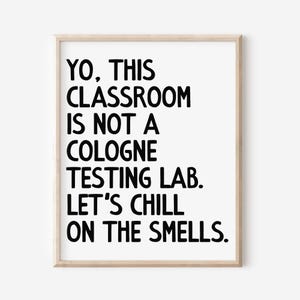 May include: A framed print with the text "YO, THIS CLASSROOM IS NOT A COLOGNE TESTING LAB. LET'S CHILL ON THE SMELLS." The text is in bold black font on a white background, framed by a light wood frame.