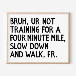 May include: A framed print with the text "BRUH, UR NOT TRAINING FOR A FOUR MINUTE MILE, SLOW DOWN AND WALK, FR." in bold black letters on a white background. The frame is a light wood colour.
