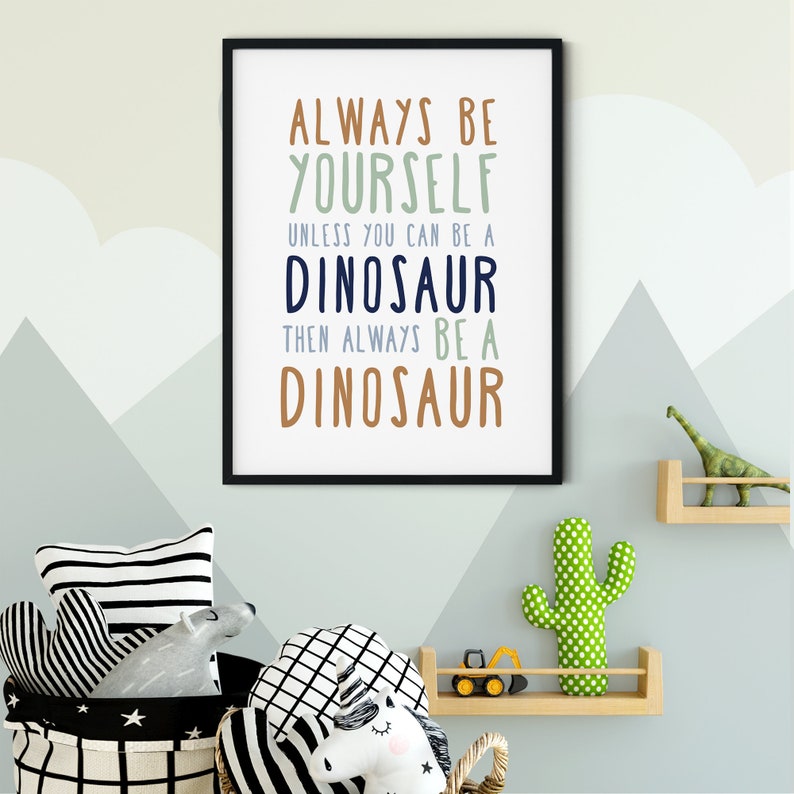 May include: A framed print with a light blue background and the text "Always be yourself unless you can be a dinosaur then always be a dinosaur". The print is hanging on a wall with a light blue and white mountain pattern.