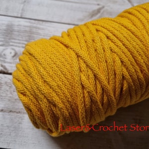 May include: A close-up of a spool of yellow cotton cord. The cord is thick and has a soft, textured surface.