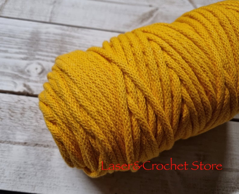 May include: A close-up of a spool of yellow cotton cord. The cord is thick and has a soft, textured surface.