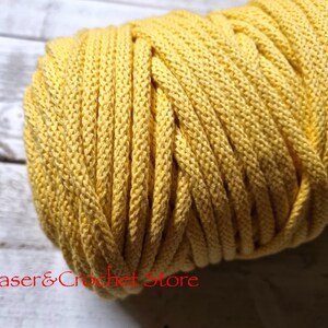 May include: A close-up of a yellow cotton cord, wound into a ball. The cord is soft and textured, and would be great for crafting projects.