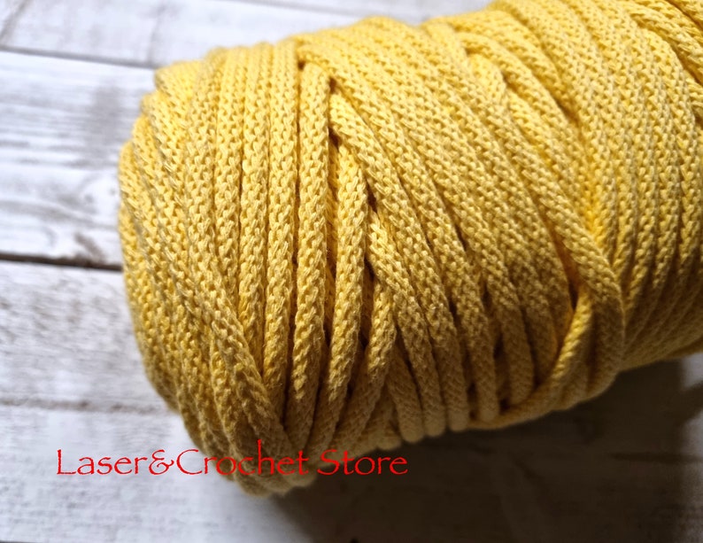 May include: A close-up of a yellow cotton cord, wound into a ball. The cord is soft and textured, and would be great for crafting projects.