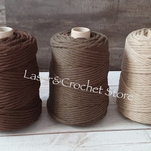 May include: Three spools of cotton rope in brown, olive green, and natural beige colours. The rope is thick and textured, perfect for macrame or other crafts.