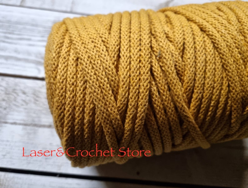 May include: A close-up of a spool of mustard yellow cotton cord. The cord is tightly wound and has a textured surface.