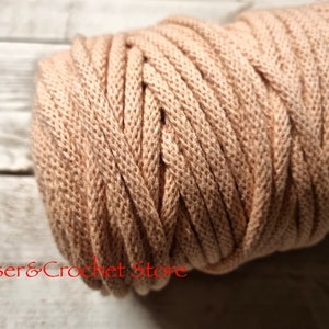 May include: A close-up of a reel of beige cotton cord. The cord is thick and has a textured surface.