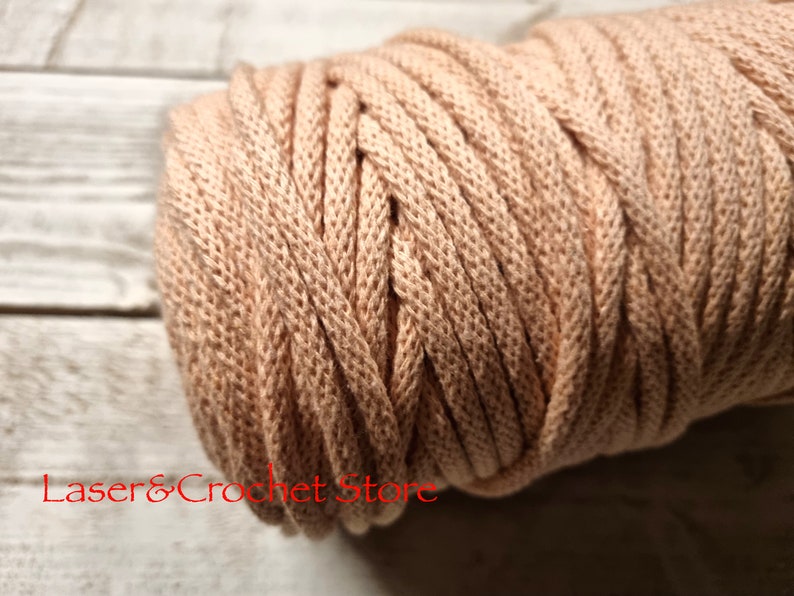May include: A close-up of a reel of beige cotton cord. The cord is thick and has a textured surface.
