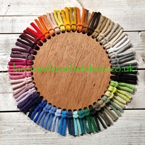 May include: A wooden circle with a variety of colours of cotton cord tied in knots around the edge. The cord is arranged in a rainbow pattern. The text "laserandcrochetstore.co.uk" is printed on the circle.