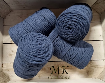Puede incluir: Cuatro carretes de cuerda de algodón azul oscuro, dispuestos en una caja de madera. La cuerda es gruesa y texturizada, y los carretes están apilados cuidadosamente. El texto "MK Cord Store" es visible en la esquina inferior derecha de la imagen.