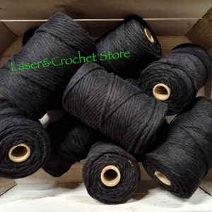 May include: A close-up of several spools of black cotton rope, arranged in a wooden crate. The rope is thick and textured, and the spools are neatly stacked. The text "Laser & Crochet Store" is visible on the top spool.