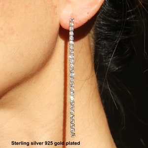May include: Sterling silver 925 gold plated long dangle earrings with a line of clear cubic zirconia stones.