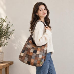 May include: A shoulder bag featuring a patchwork design composed of square leather panels in various shades of brown, tan, gray, and black. The bag has a single dark brown leather shoulder strap with a gold-toned metal buckle adjustment.