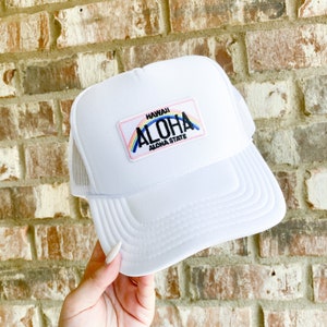 Puede incluir: Gorra de camionero blanca con un parche rosa, azul y arcoíris que dice "Hawaii Aloha State".