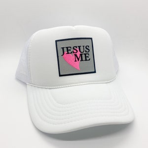 May include: White trucker hat with a gray patch that says "JESUS ME" in black text with a pink heart.