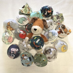 May include: A collection of 17 colourful fabric baby teethers with various animal and nature designs. A brown and white stuffed dog toy is in the centre of the teethers.