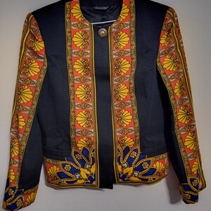 May include: A black blazer with a colourful patterned design featuring yellow, red and blue accents. The pattern includes stylised seashells and geometric shapes.