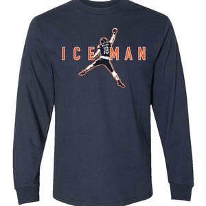 May include: Navy blue long-sleeve shirt featuring a graphic of a football player in mid-air with the text "ICEMAN" in orange. The player's jersey number is 18. The shirt is a solid color and has a crew neck.