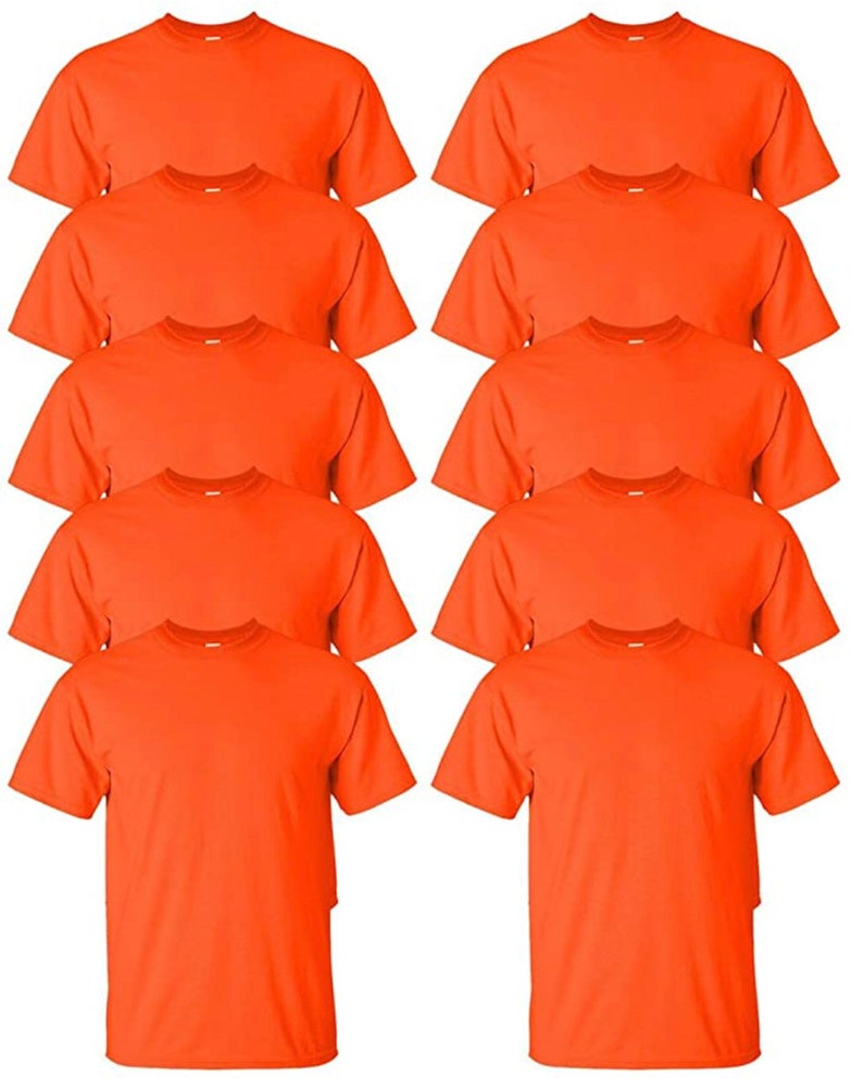 May include: A stack of ten orange crew neck t-shirts. The shirts are made of a soft material and have short sleeves. The shirts are a solid orange color.