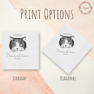 May include: Two white napkins with a black and white illustration of a cat with a halo. The text "I loved her first" is printed on both napkins. The napkins are shown in two different orientations: straight and diagonal.