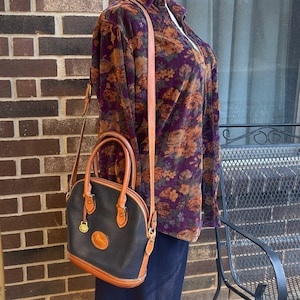 Dooney & Bourke Black and Tan All Weather Leather Norfolk Shoulder Bag with Top Handles, Shoulder Strap, Brass Duck Fob, and Key Ring
