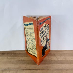 May include: A vintage Wonder Book titled How the Rabbit Fooled the Whale and the Elephant and Other Stories. The orange cover features a black rabbit illustration, while the back panel displays a list of other books in the series with text.