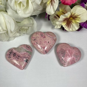 May include: Three pink and white heart-shaped stones with a marbled pattern.