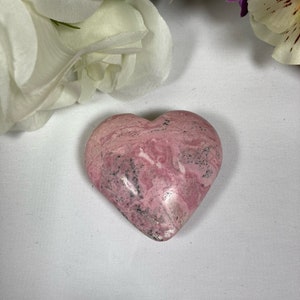 May include: A pink and white heart-shaped stone with a marbled pattern.