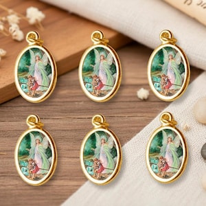 May include: Six gold-toned oval pendants with a detailed painted image of an angel and two children. The pendants have a loop at the top for hanging. The background includes a wooden surface, flowers, and small stones.