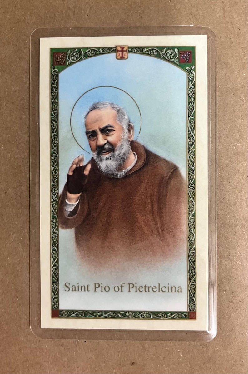 May include: A religious card featuring an illustration of Saint Pio of Pietrelcina. The image shows a man with a white beard and a halo, wearing a brown robe. The card has a decorative border and the saint's name is printed at the bottom.