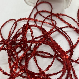 May include: Red metallic trim with a sparkly finish. The trim is thin and has a slightly textured surface.